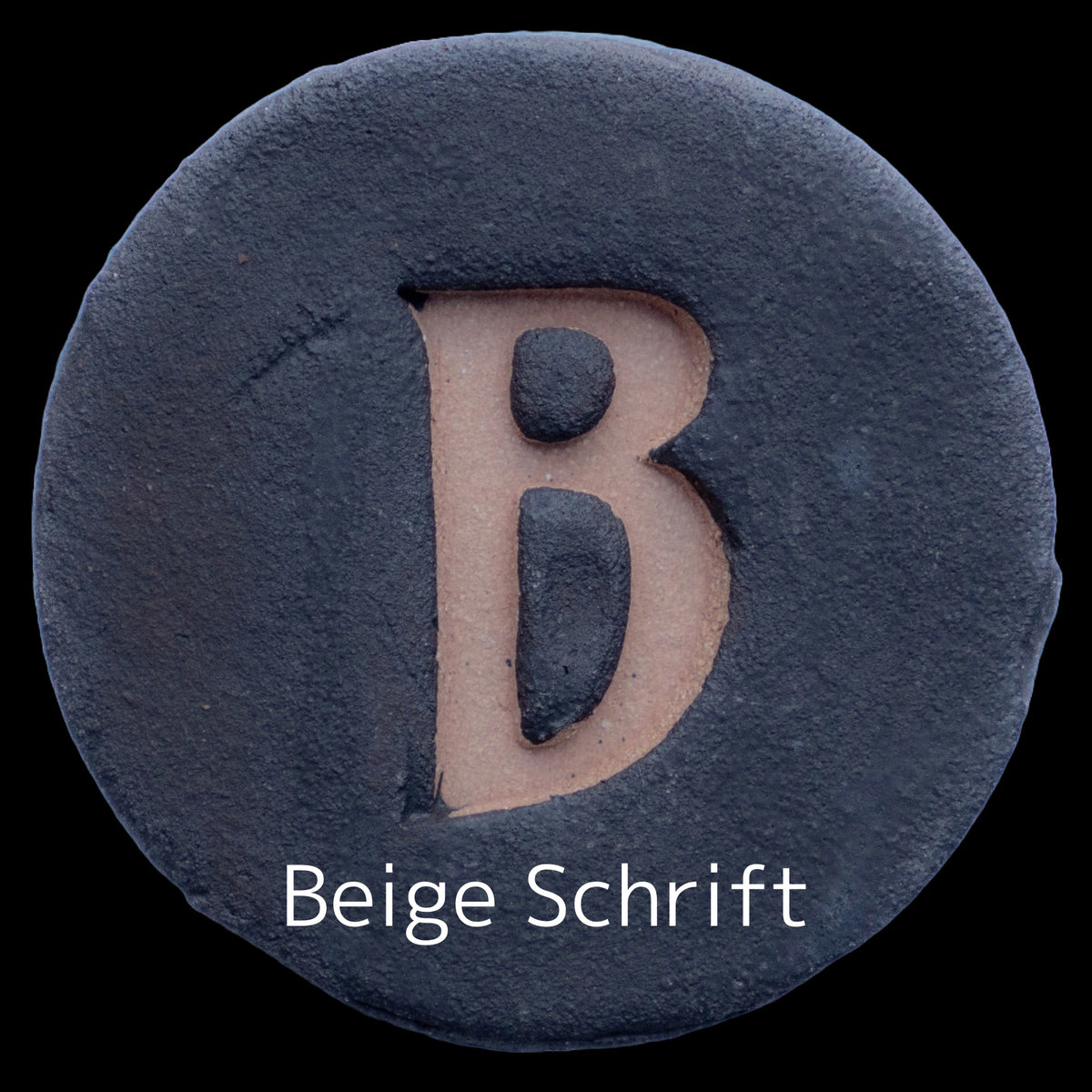 Runde dunkle Keramikplatte mit graviertem beigen Buchstaben B in der Mitte, beschriftet mit 'Beige Schrift