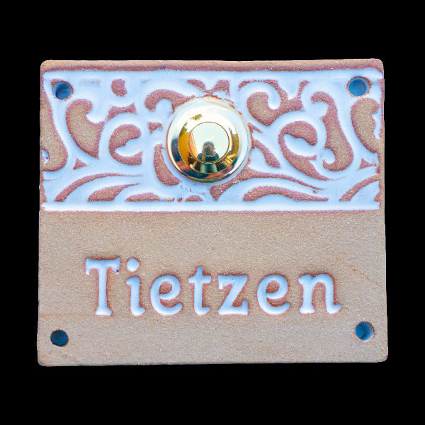 Rechteckige keramische Türklingelplatte in Beige mit weißem Blumenornament und eingraviertem Namen 'Tietzen', mit goldenem Knopf in der Mitte