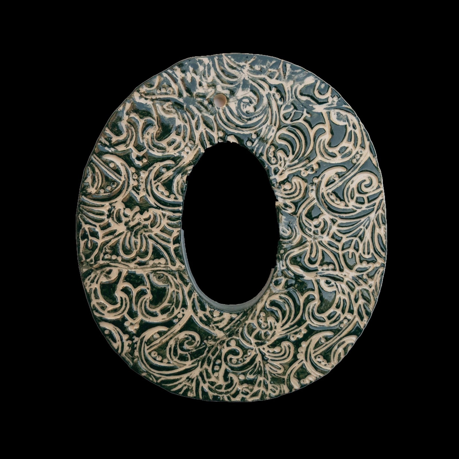 Handgefertigte Keramik-Hausnummer „0“ in Braun mit schwarzen Ornamentmustern, vor schwarzem Hintergrund dargestellt.