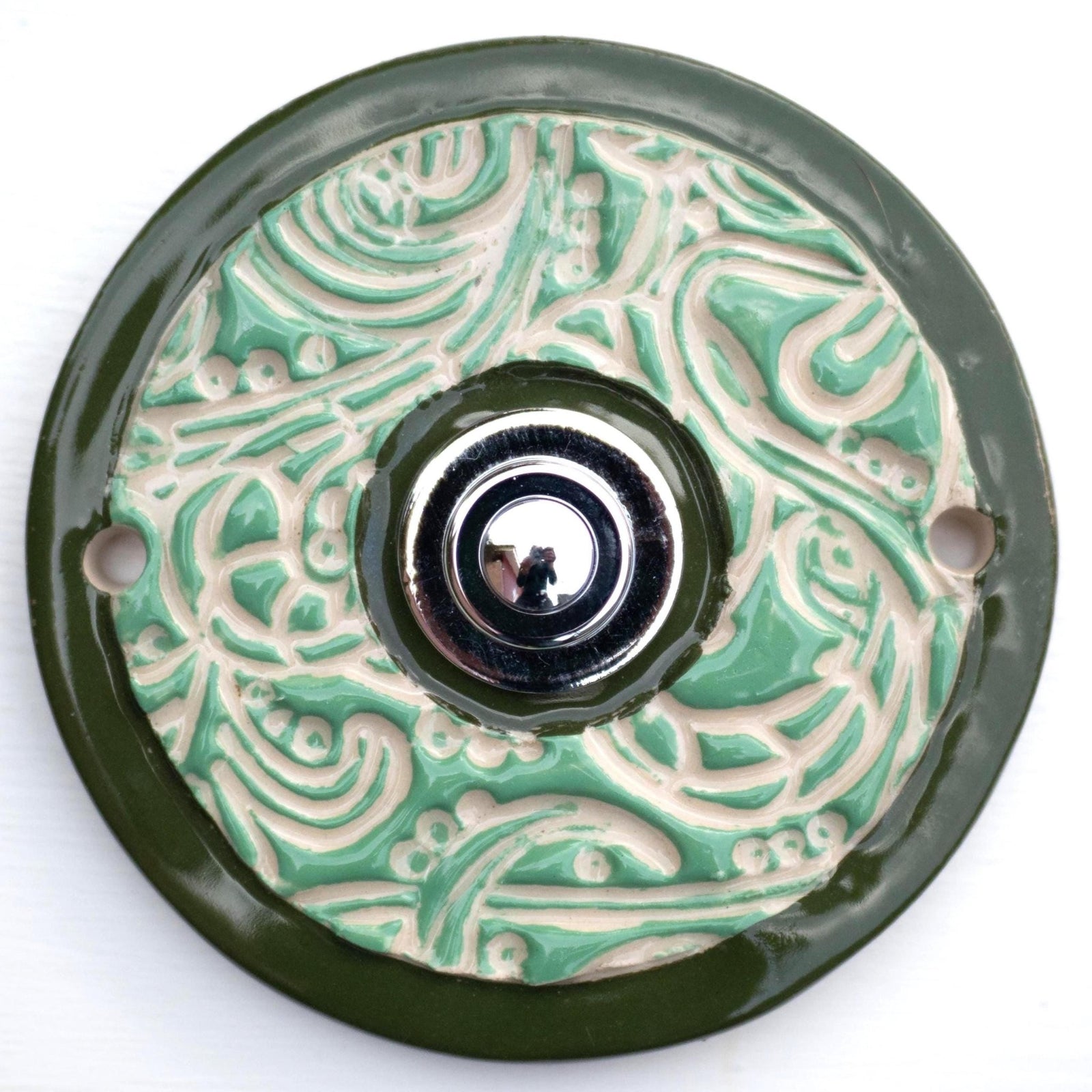 Elegante Keramiktürklingel in Grün mit detailliertem Ornamentdesign und klassischem Druckknopf. Handgefertigt, langlebig und einfach zu montieren.