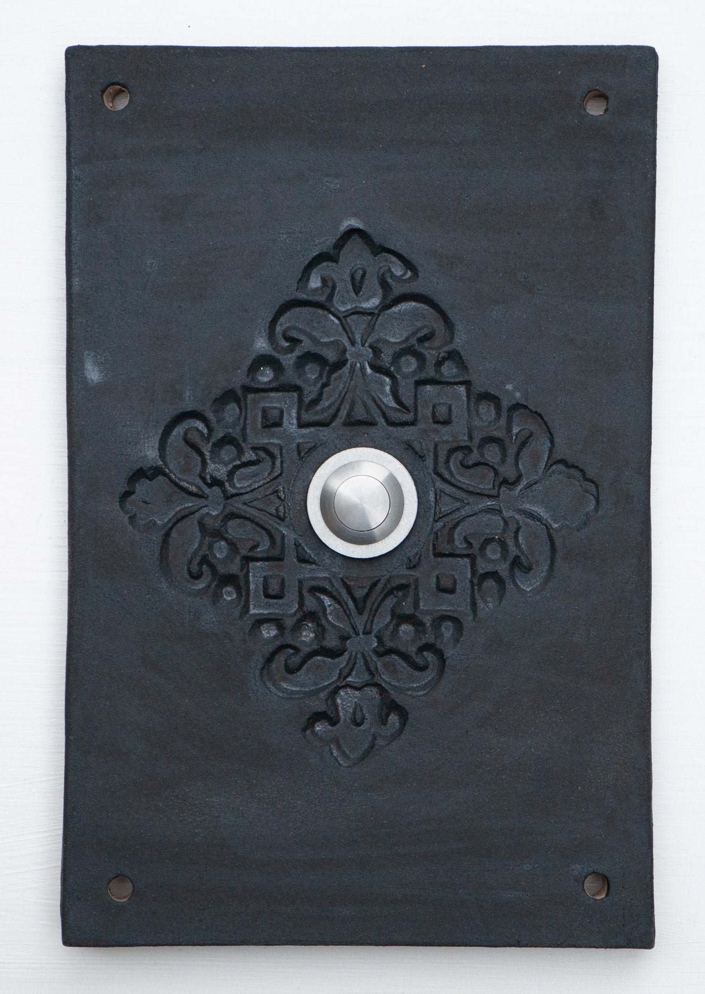 Rein schwarze Keramik-Klingelplatte mit erhabenem ornamentalem Blumenmuster und mittigem Silberknopf.
