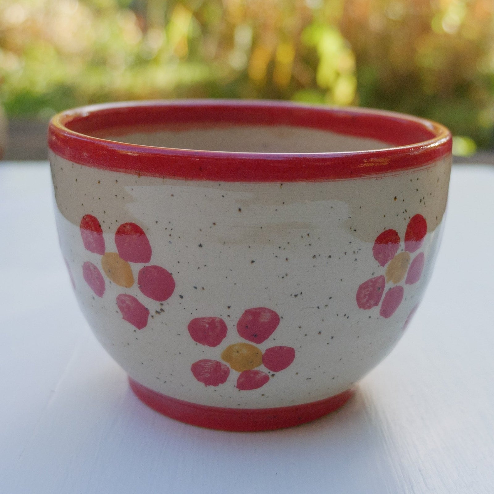 Handbemalter Keramikbecher mit rotem Blumenmuster, gelben Blütenmitten und rotem Rand