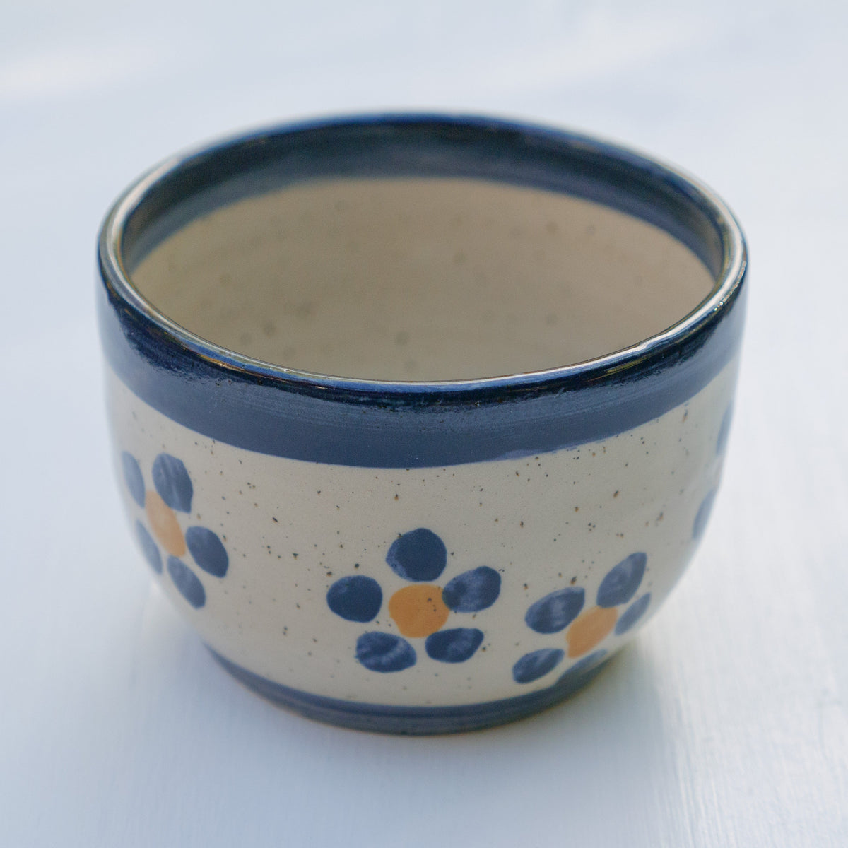 Handbemalter Keramikbecher mit blau-gelbem Blumenmuster und dunkelblauem Rand