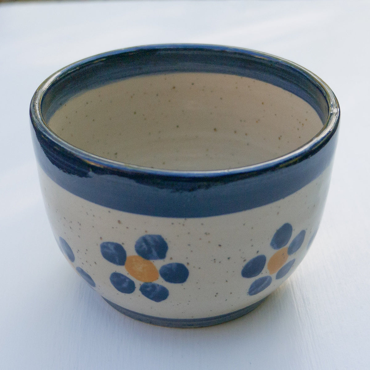 Handbemalter Keramikbecher mit blau-gelbem Blumenmuster und dunkelblauem Rand