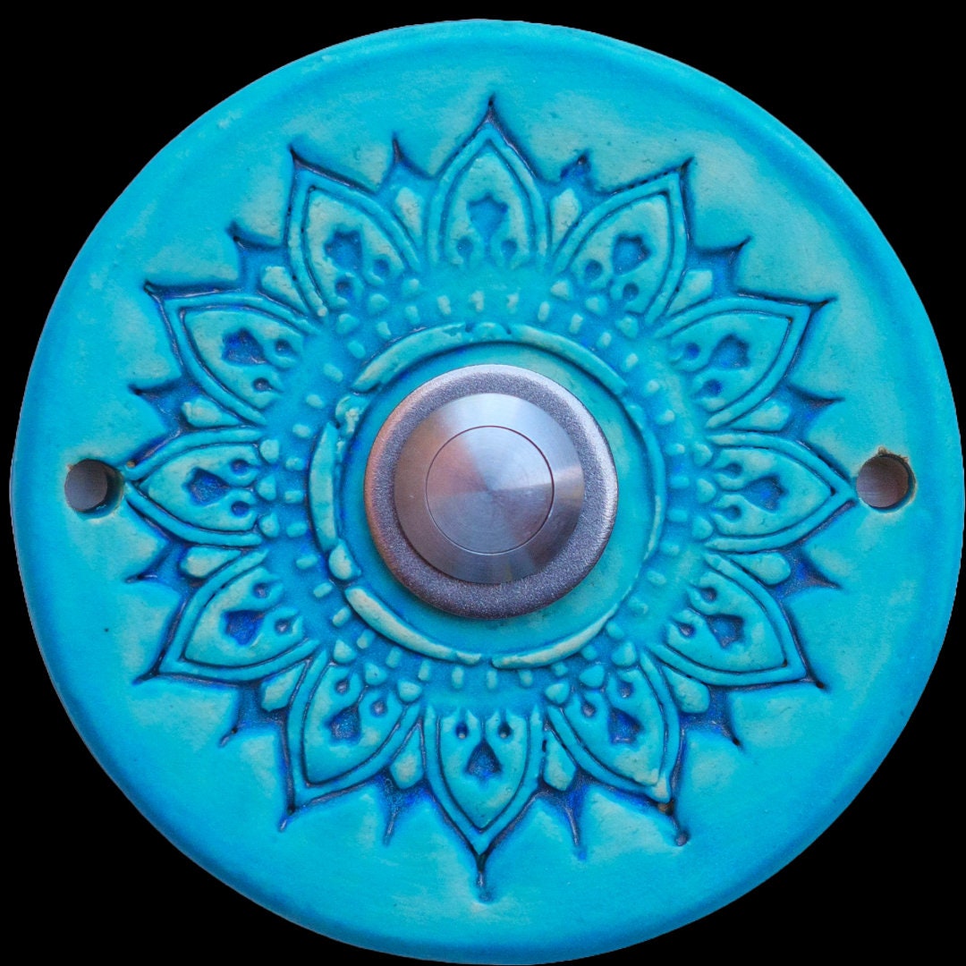 Handgefertigte Keramiktürklingel in Türkis mit filigranem Mandala-Blumenmuster. Der silberne Knopf verleiht einen modernen Akzent und macht dieses Stück sowohl künstlerisch als auch funktional. Eine einzigartige Möglichkeit, Ihre Gäste stilvoll zu empfangen.