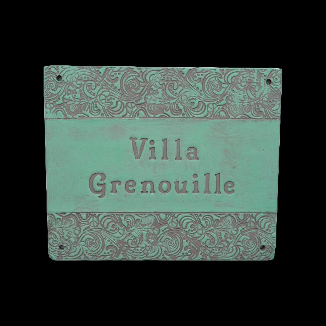 Rechteckiges Keramik-Türschild in Türkis mit verziertem floralem Randmuster und eingraviertem Text Villa Grenouille