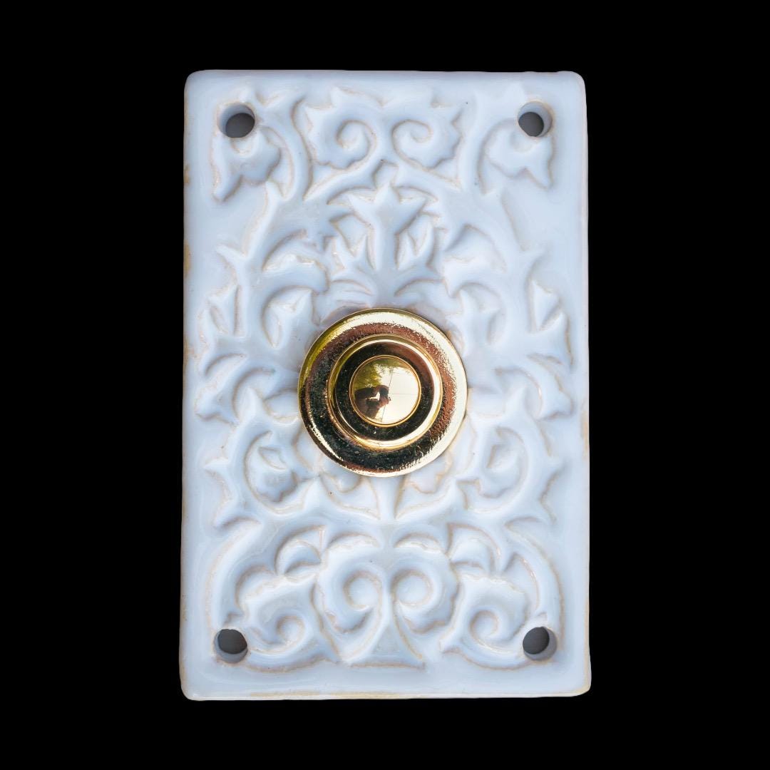 Rechteckige Keramikklingel in Rein-Weiß mit verziertem Reliefmuster und goldenem Druckknopf in der Mitte