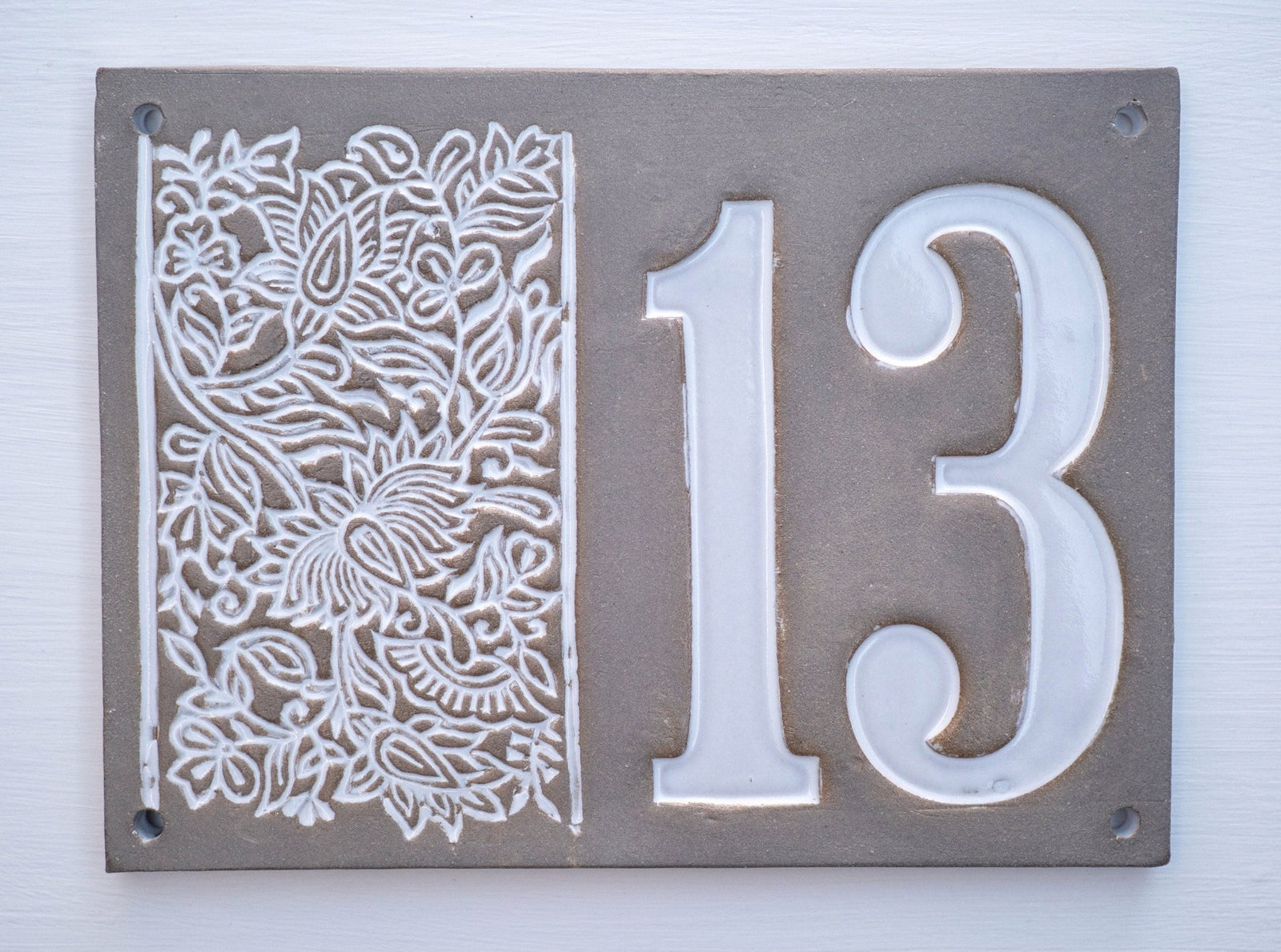 Rechteckiges graues Keramik-Hausschild mit erhabenen weißen Ziffern 13 und floralem Dekor