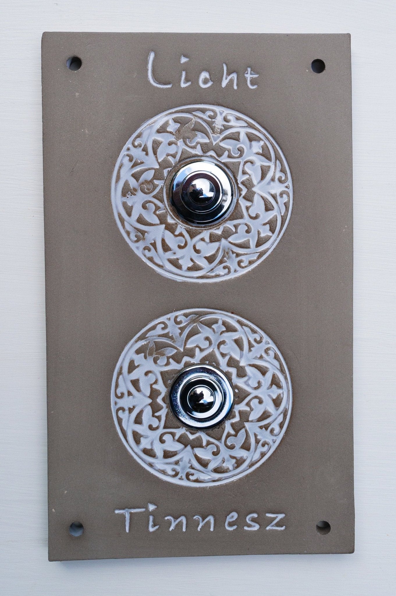 Rechteckige graue Keramik-Klingelplatte mit zwei verzierten runden silbernen Knöpfen und den eingravierten Namen 'Licht' und 'Tinnesz'.