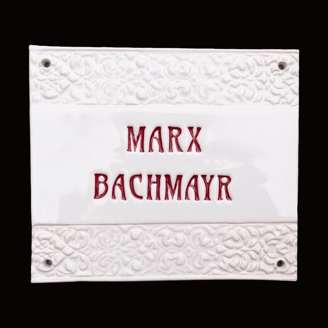 Handgefertigtes Keramikschild mit geprägten Zierbordüren, glänzend weißem Hintergrund und individuellem Text „Marx Bachmayr“ in Rot