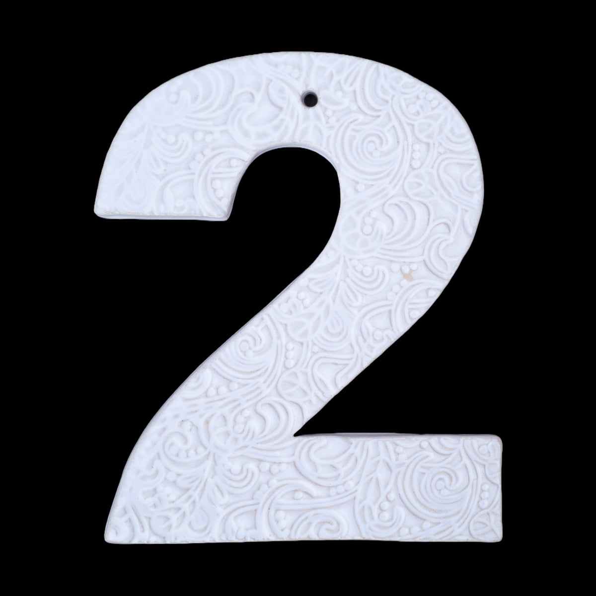 Handgefertigte Keramik-Hausnummer „2“ in Weiß mit geprägtem ornamentalen Wirbelmuster, vor schwarzem Hintergrund dargestellt.