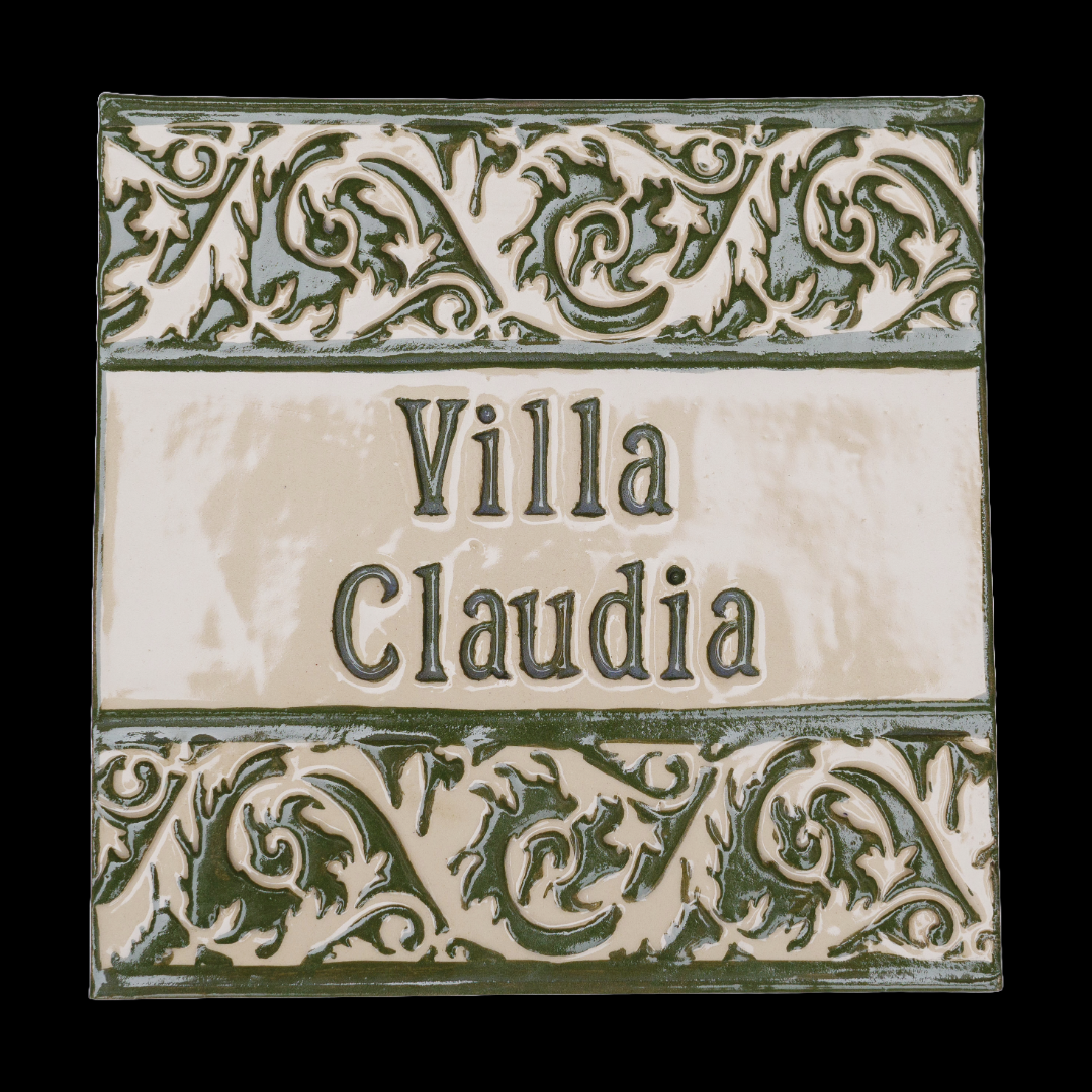 Handgefertigte Keramikfliese mit verziertem Rankenrelief in glänzendem grünen Engobe, mit individuellem Text „Villa Claudia“ auf cremefarbenem Hintergrund.
