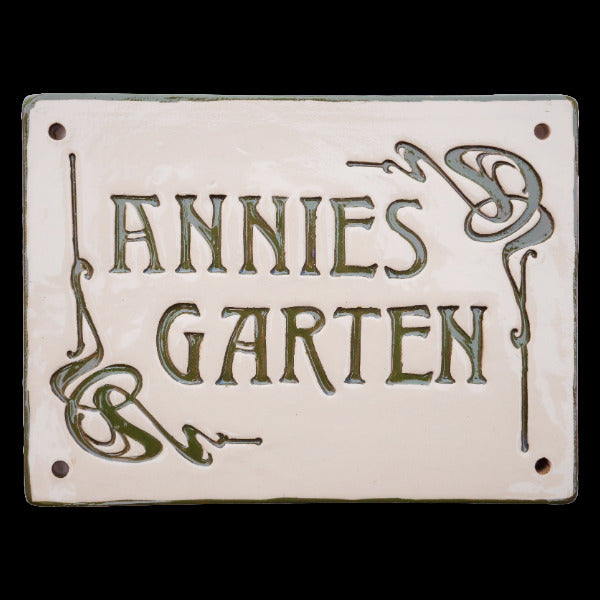 Rechteckiges Keramikschild mit dekorativen Eckverzierungen und der Gravur „Annies Garten.