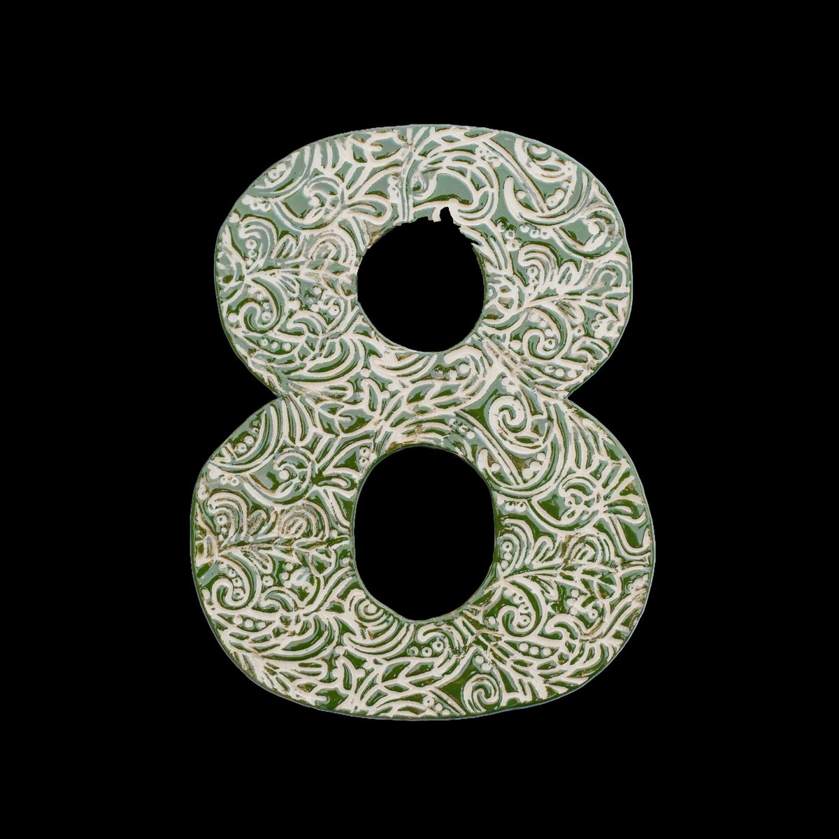 Handgefertigte Keramik-Hausnummer „8“ in Grün mit beigefarbenen Ornamentmustern, vor schwarzem Hintergrund dargestellt.