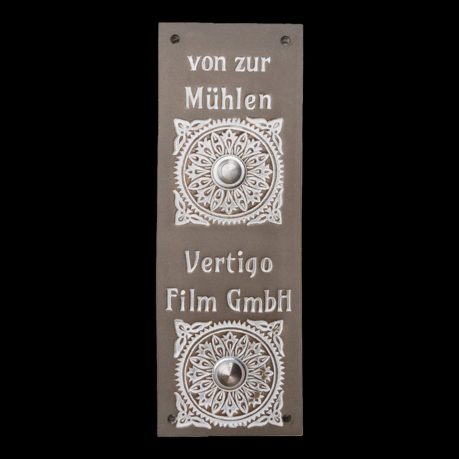 Rechteckige graue Keramik-Klingelplatte mit zwei silbernen Knöpfen, verziert mit Blumenornamenten und den eingravierten Namen 'von zur Mühlen' und 'Vertigo Film GmbH