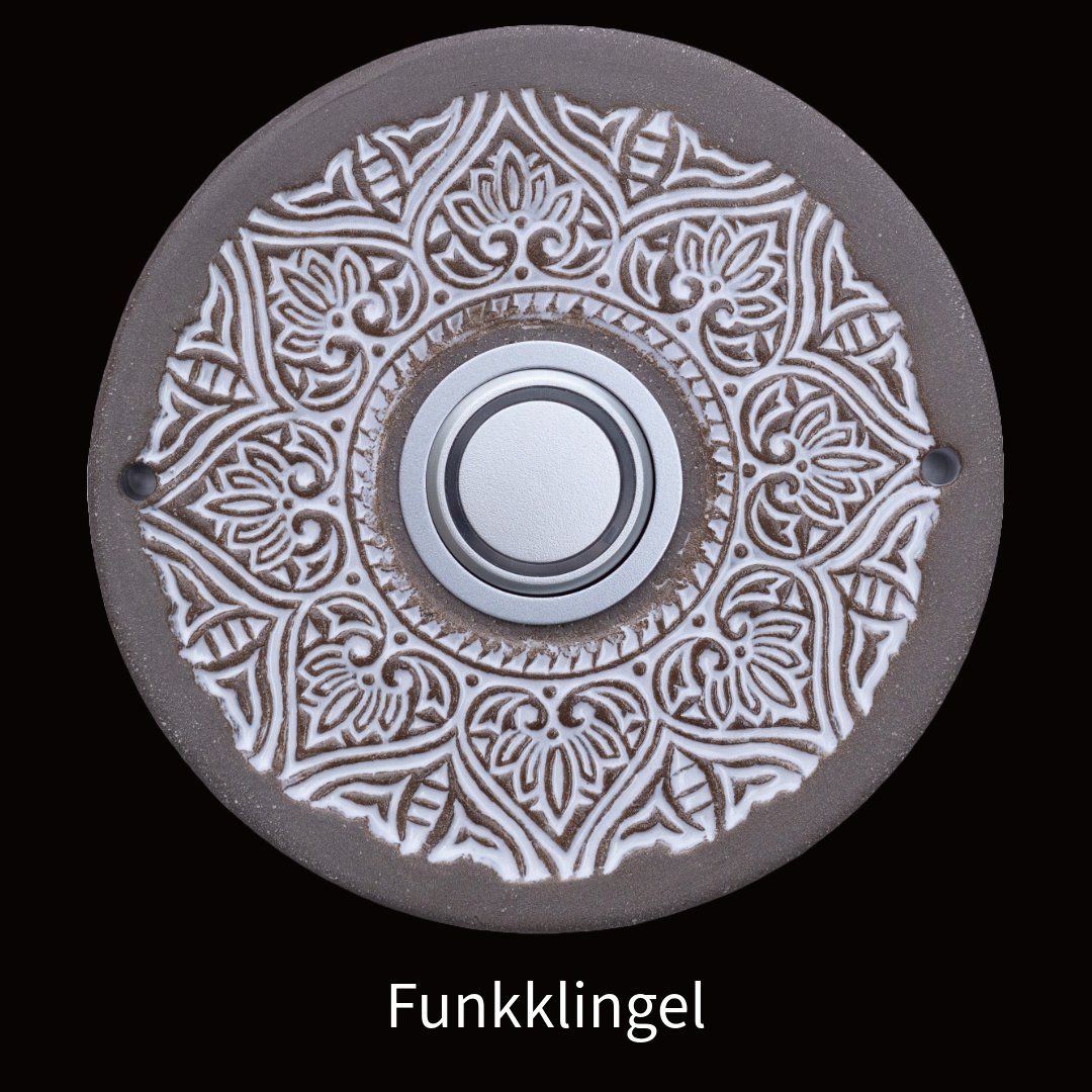 Runde Keramiktürklingel mit filigranem weißem Mandala-Blumenmuster und silbernem Knopf in der Mitte. Beschriftet als 'Funkklingel'