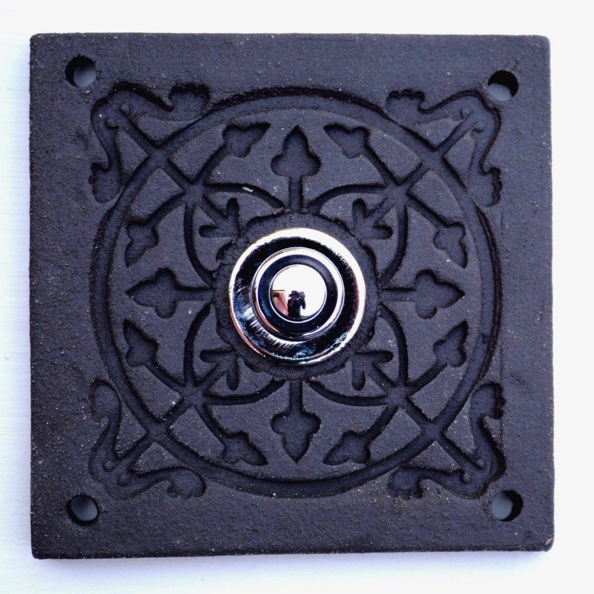 Quadratische Keramikklingel in Rein-Schwarz mit geprägtem Mandala-Muster und silbernem Druckknopf in der Mitte.