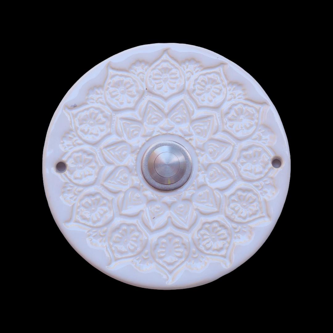 Runde Keramikklingel mit filigranem, spitzenartigem Blumenmuster in Weiß und zentralem silbernen Knopf