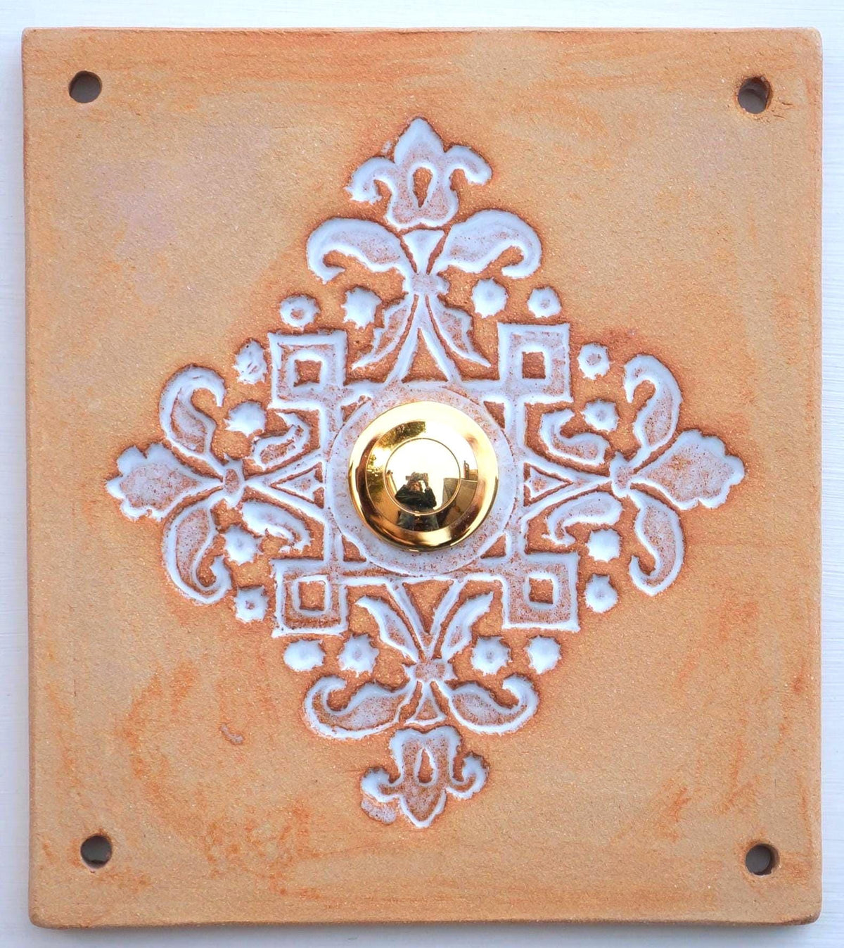 Rechteckige keramische Klingelplatte in Terrakottafarbe mit ornamentaler Prägung in Blumenmotiven und mittigem goldenen Knopf