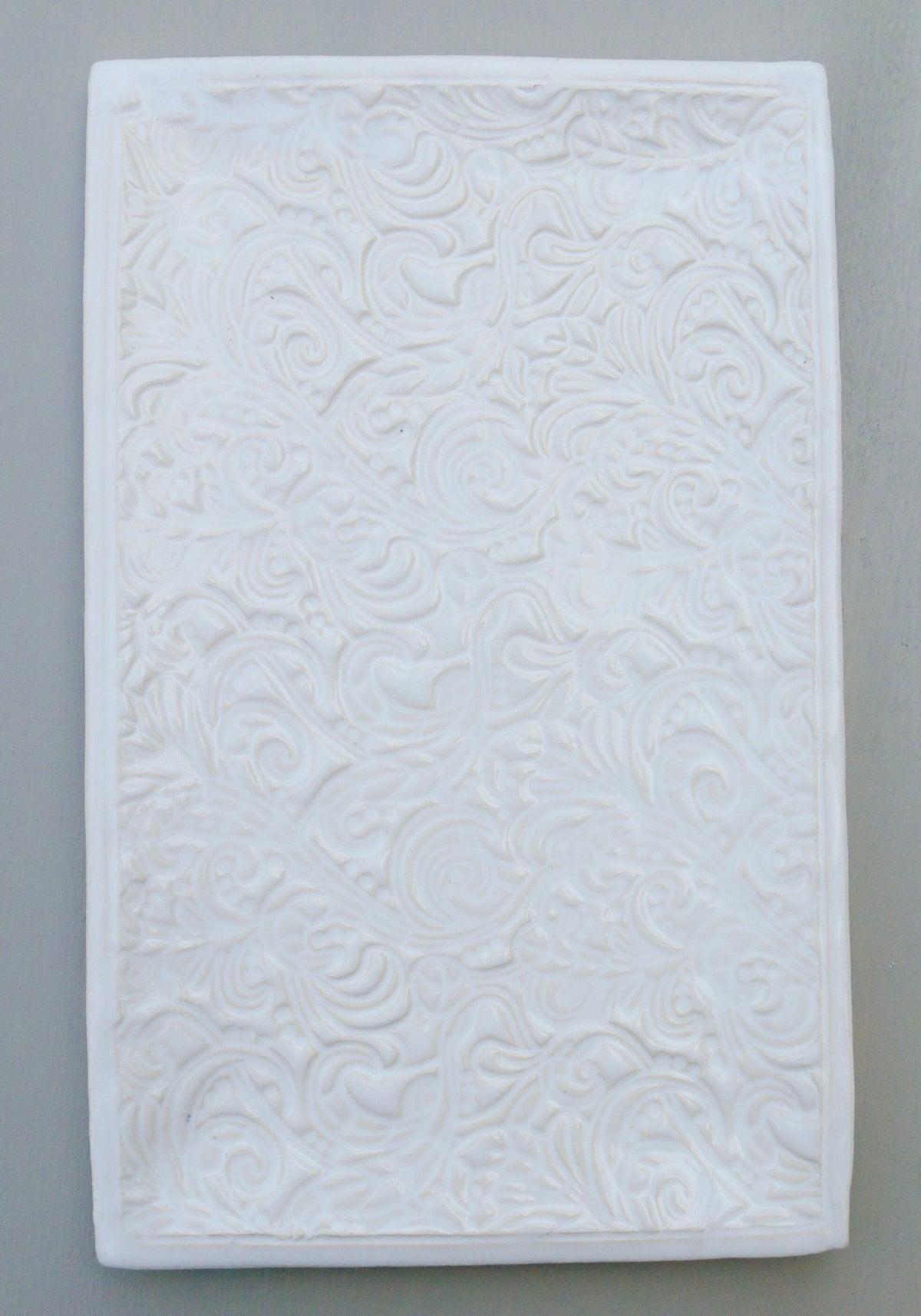 Rechteckige weiße Keramikfliese mit geprägtem Blumen- und Wirbelmuster