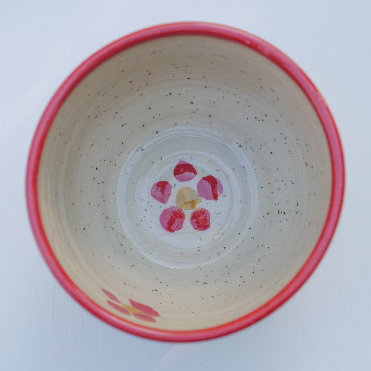 Handbemalter Keramikbecher mit rotem Blumenmuster, gelben Blütenmitten und rotem Rand