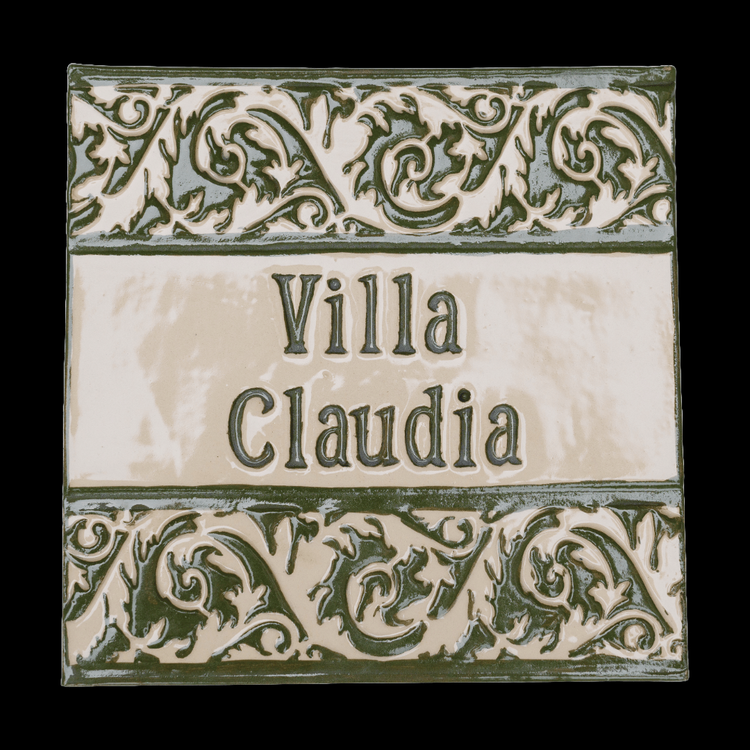 Handgefertigte Keramikfliese mit verziertem Rankenrelief in glänzendem grünen Engobe, mit individuellem Text „Villa Claudia“ auf cremefarbenem Hintergrund.