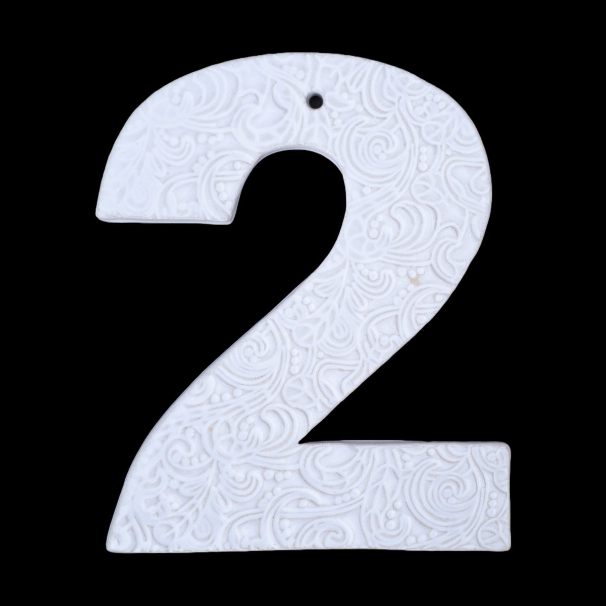 Handgefertigte Keramik-Hausnummer „2“ in Weiß mit geprägtem ornamentalen Wirbelmuster, vor schwarzem Hintergrund dargestellt.