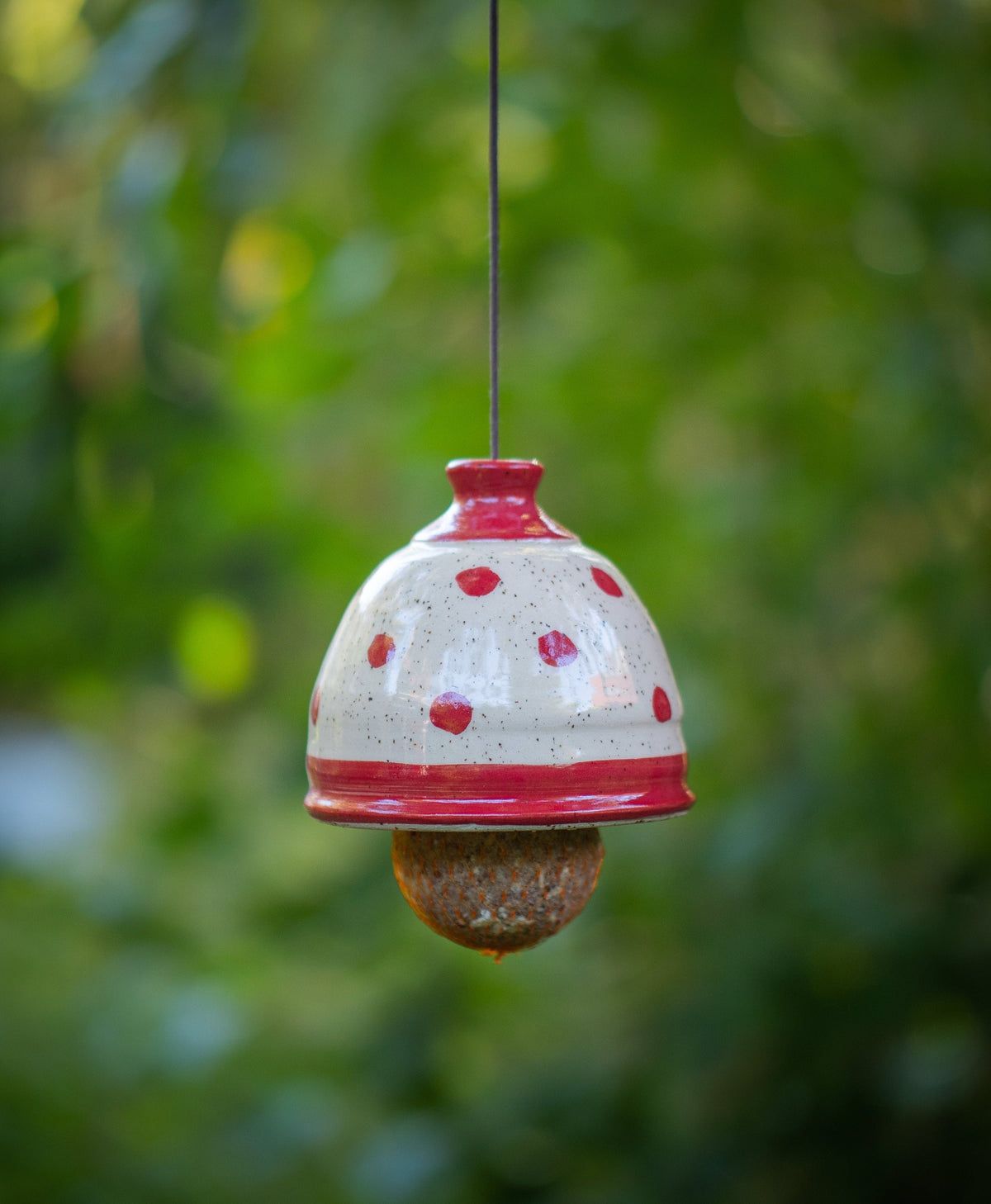 Handgetöpfertes Keramik-Vogelfutterhaus mit roten Punkten, hängend im Freien mit Meisenknödel