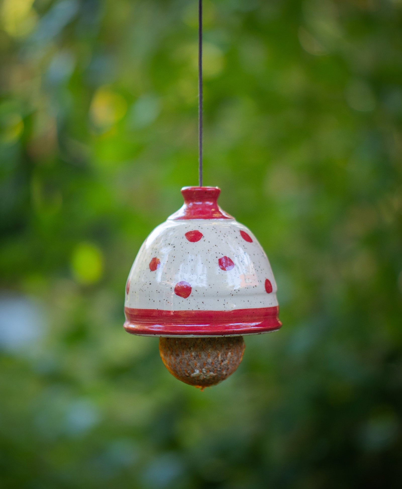 Handgetöpfertes Keramik-Vogelfutterhaus mit roten Punkten, hängend im Freien mit Meisenknödel