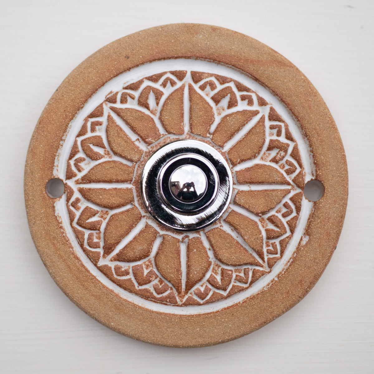 Runde dekorative Klingel mit geprägtem weißem Mandala-Blumenmuster auf goldbrauner Platte und silbernem Druckknopf in der Mitte