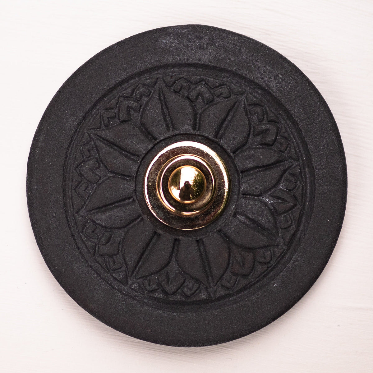 Runde dekorative Klingel mit geprägtem Mandala-Blumenmuster auf schwarzer Platte und silbernem Druckknopf in der Mitte
