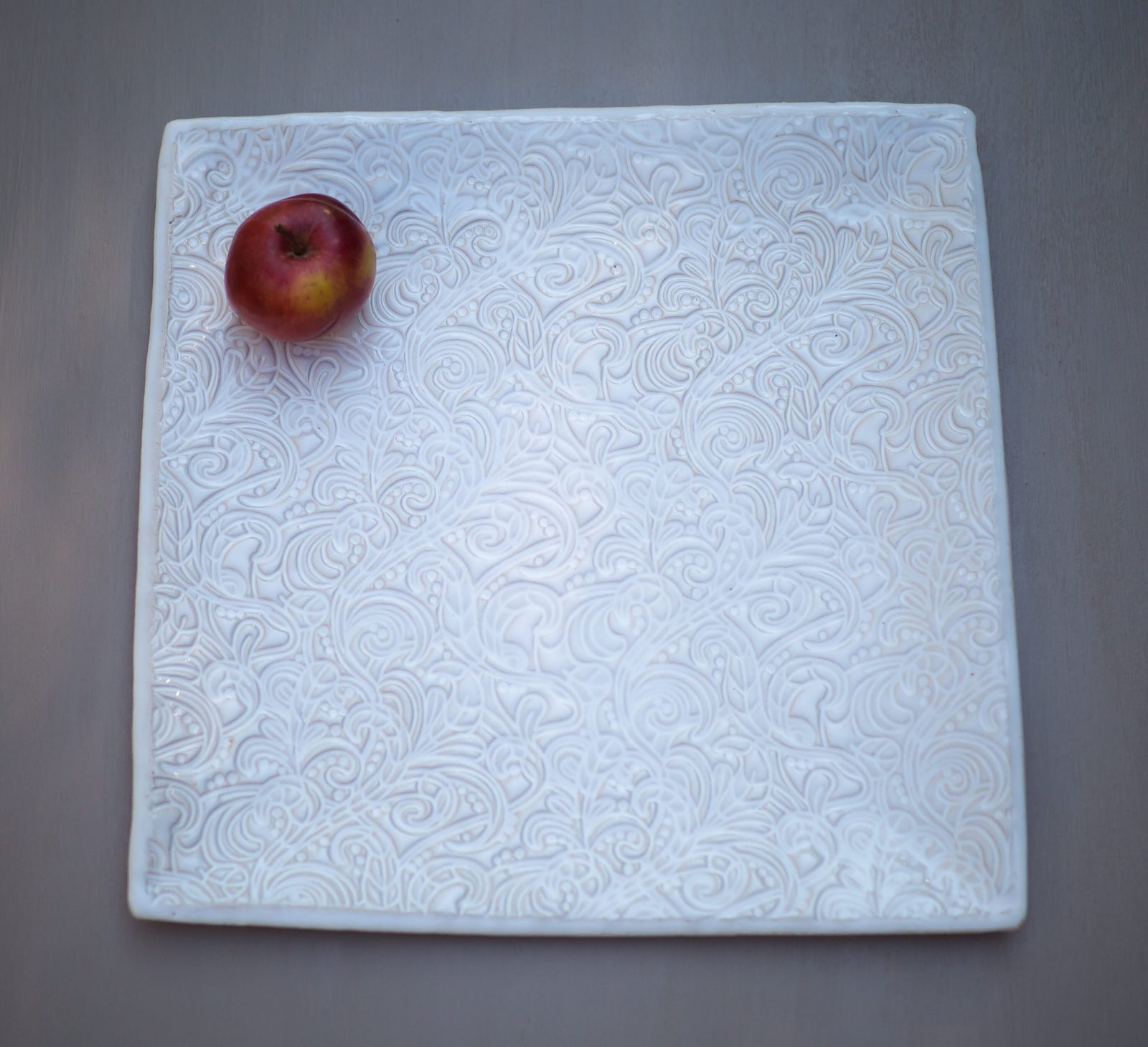 Weiße Keramikfliese mit aufwendig geprägtem Blumen- und Wirbelmuster