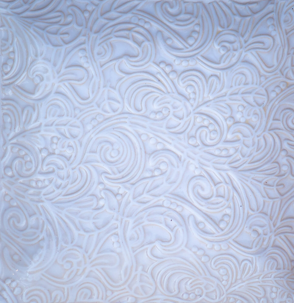 Weiße Keramikfliese mit aufwendig geprägtem Blumen- und Wirbelmuster