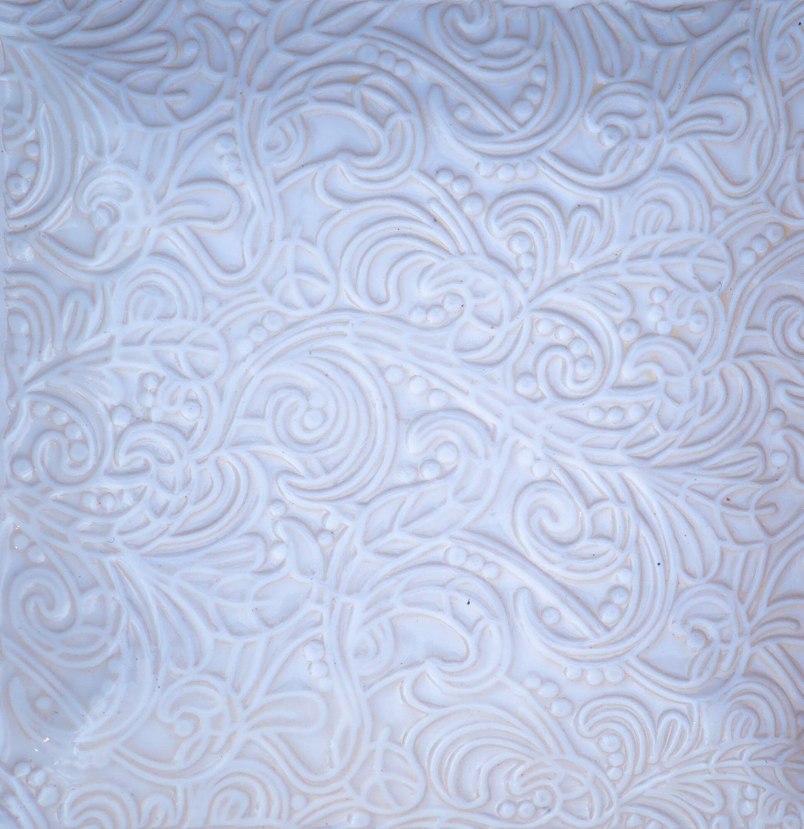 Weiße Keramikfliese mit aufwendig geprägtem Blumen- und Wirbelmuster