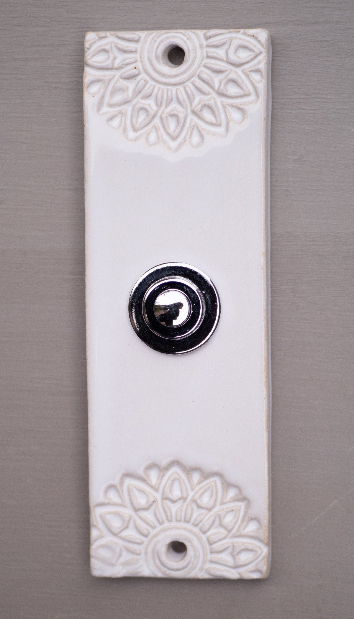 Handgefertigte weiße Keramik-Klingelplatte mit geprägtem Blumenmuster und silbernem Knopf – minimalistisches Eingangsdekor