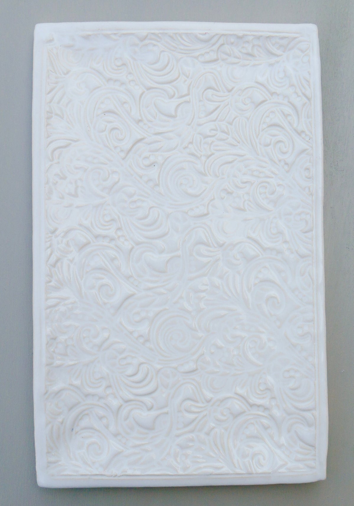 Rechteckige weiße Keramikfliese mit geprägtem Blumen- und Wirbelmuster