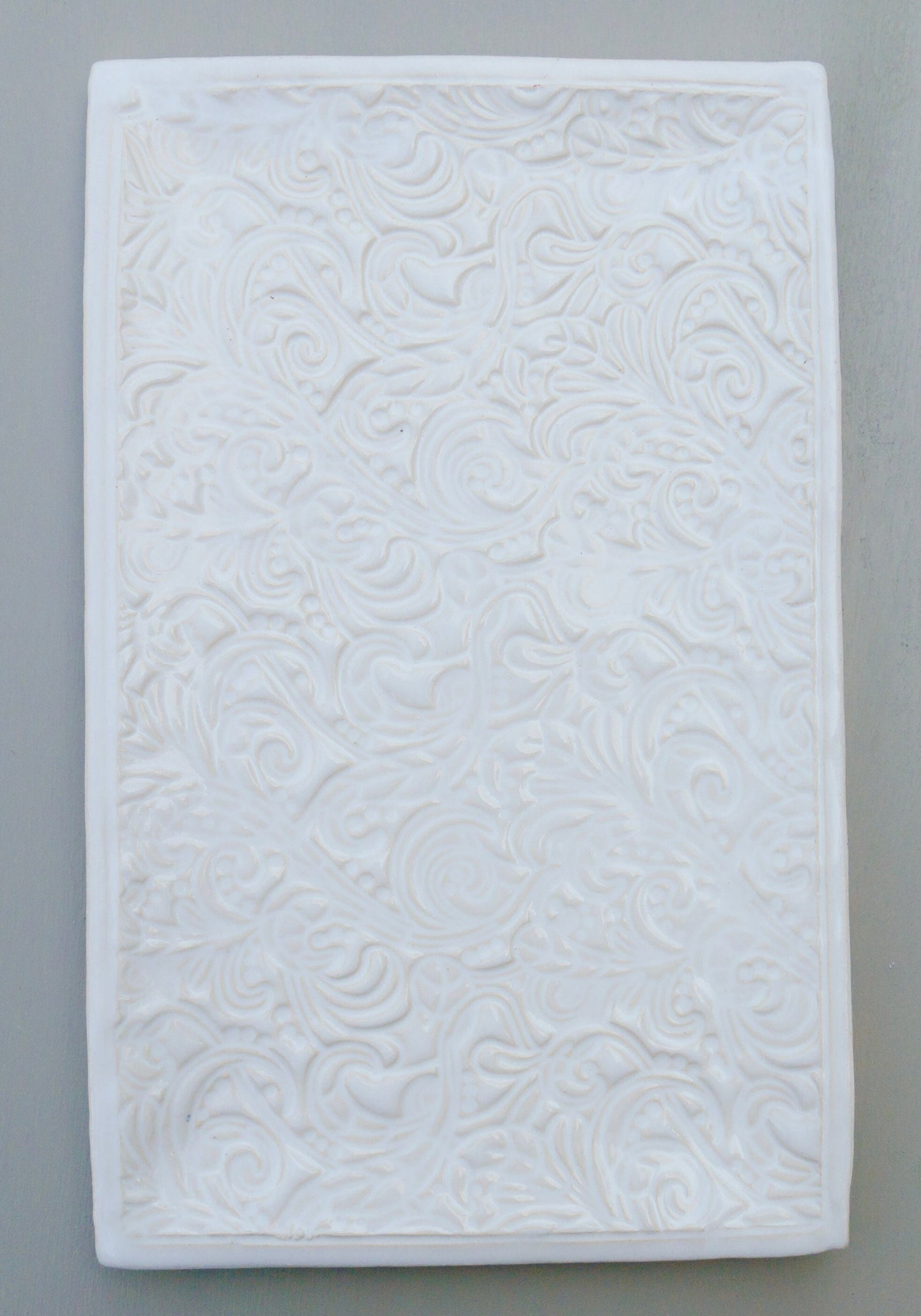 Rechteckige weiße Keramikfliese mit geprägtem Blumen- und Wirbelmuster