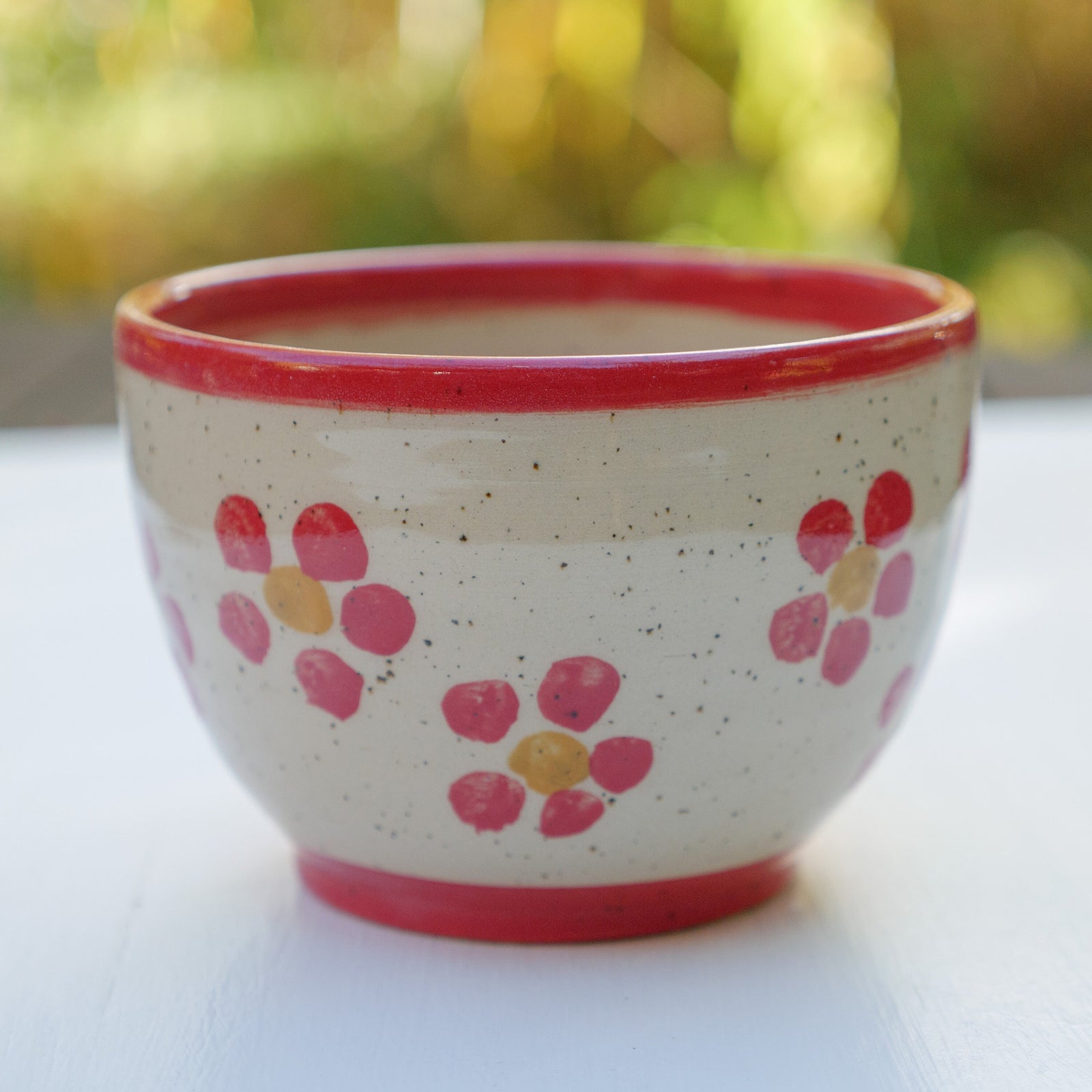 Handbemalter Keramikbecher mit rotem Blumenmuster, gelben Blütenmitten und rotem Rand