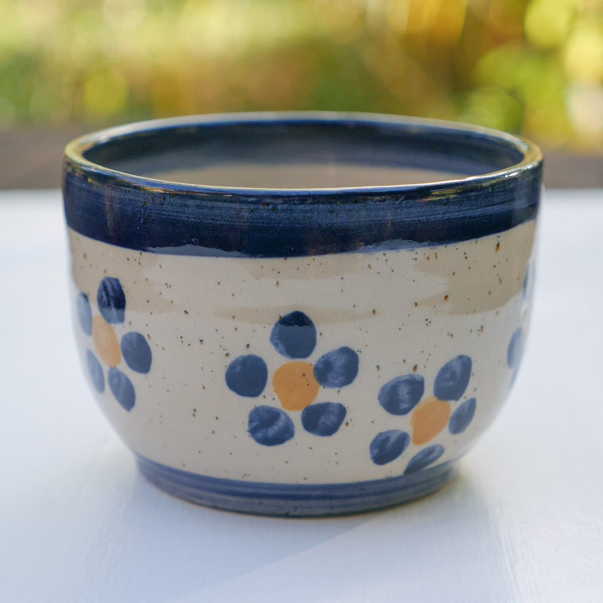 Handbemalter Keramikbecher mit blau-gelbem Blumenmuster und dunkelblauem Rand