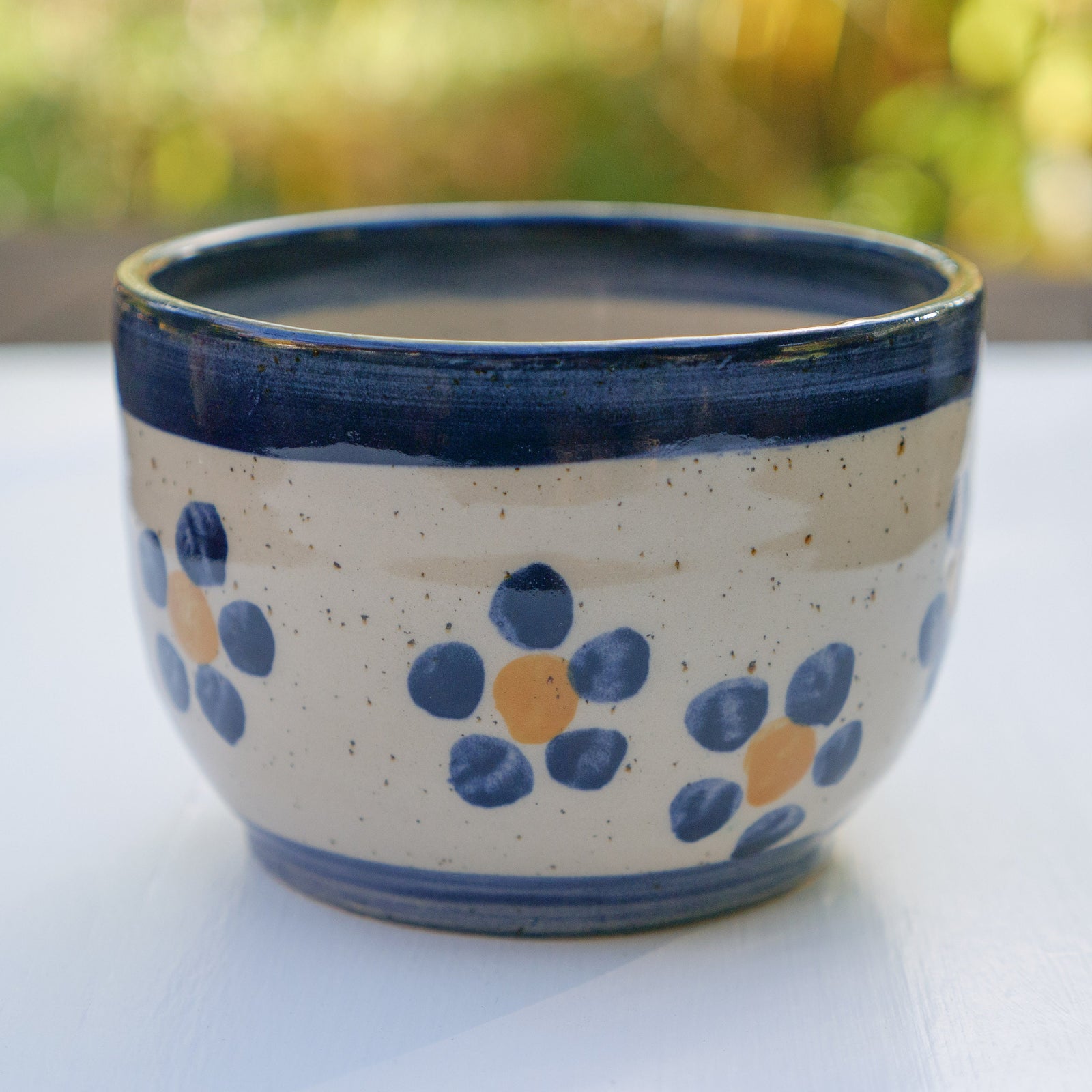 Handbemalter Keramikbecher mit blau-gelbem Blumenmuster und dunkelblauem Rand