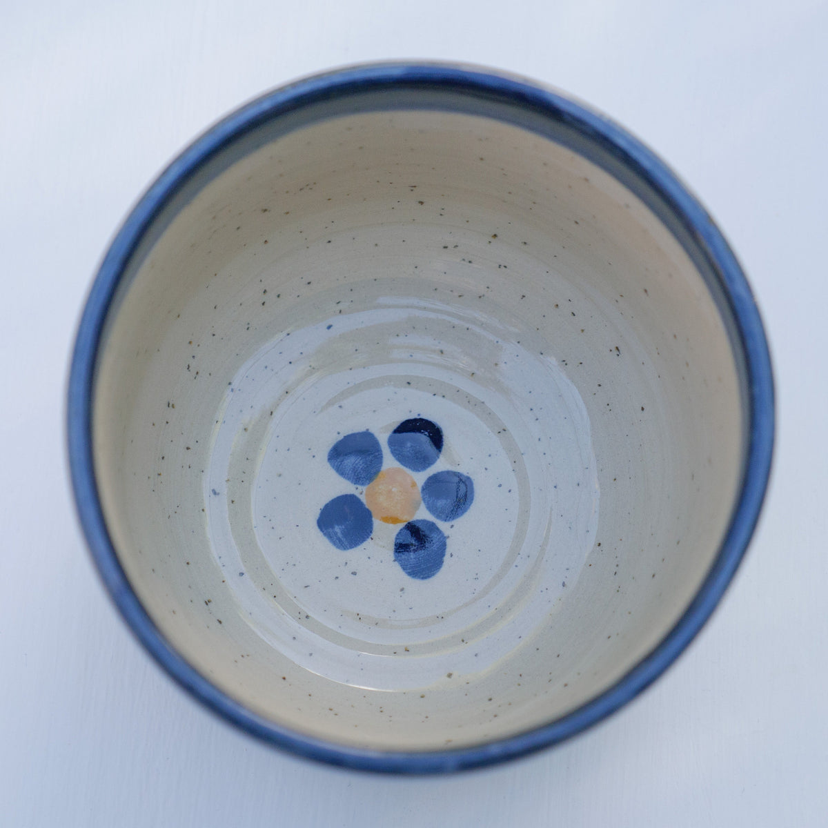 Handbemalter Keramikbecher mit blau-gelbem Blumenmuster und dunkelblauem Rand