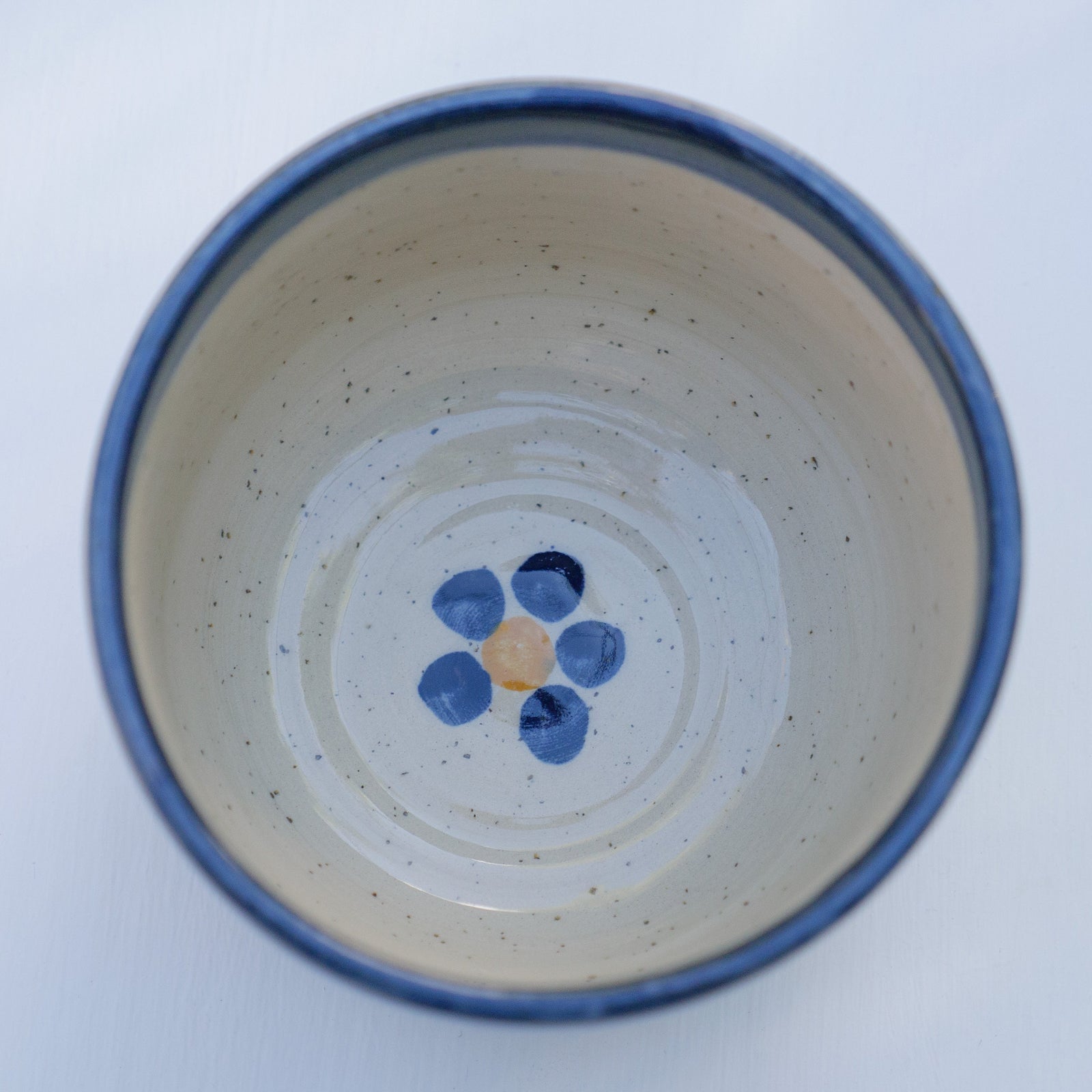Handbemalter Keramikbecher mit blau-gelbem Blumenmuster und dunkelblauem Rand
