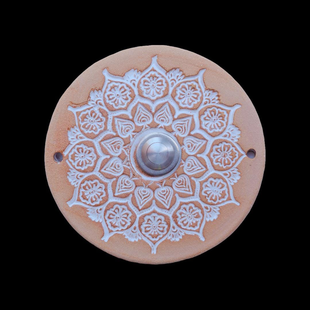 Runde Keramikklingel mit filigranem, spitzenartigem Blumenmuster in Weiß und zentralem silbernen Knopf