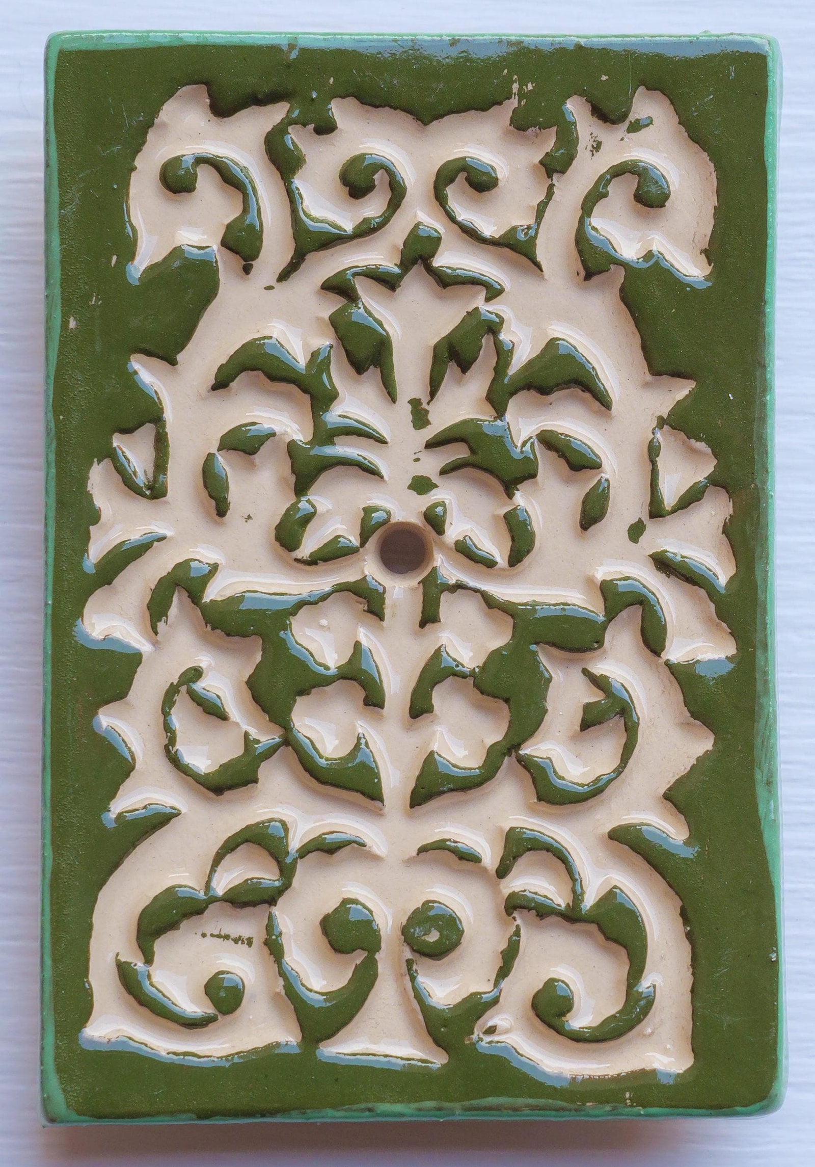 Rechteckige Keramik-Klingelplatte mit grünem Hintergrund und beigem Ornamentmuster in Blumenform