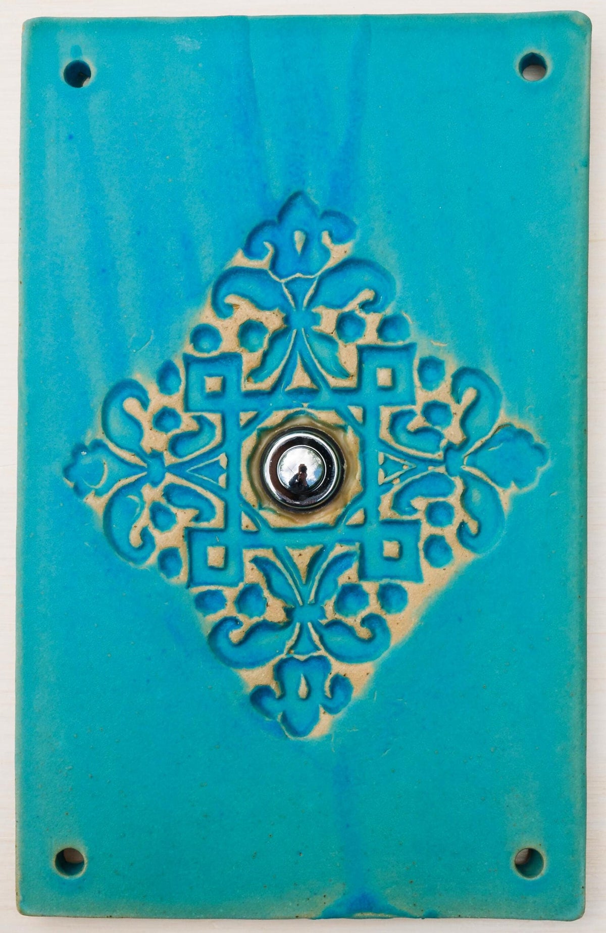 Rechteckige türkise keramische Klingelplatte mit ornamentaler Prägung in Blumenmotiven und mittigem silbernem Knopf