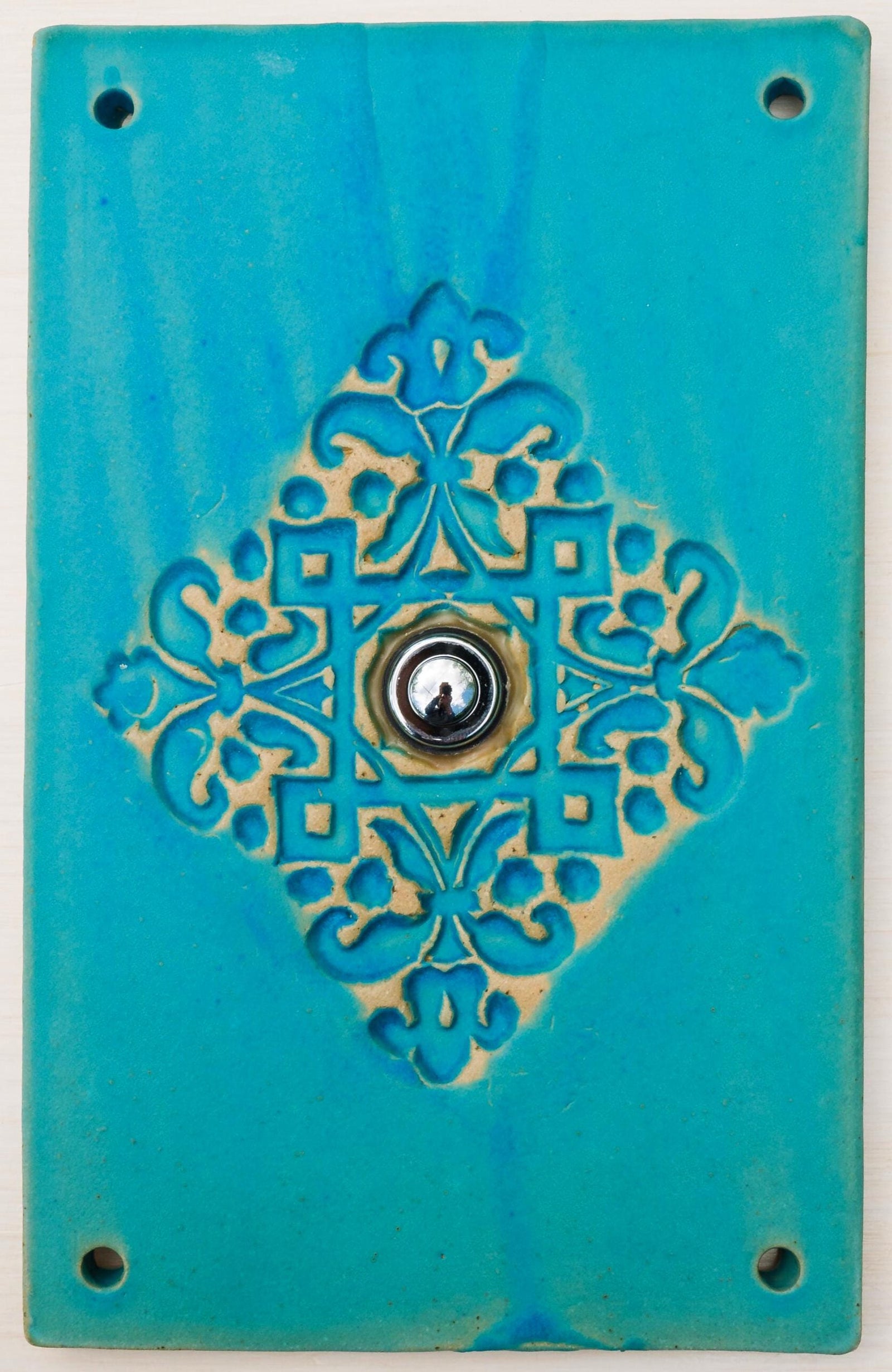 Rechteckige türkise keramische Klingelplatte mit ornamentaler Prägung in Blumenmotiven und mittigem silbernem Knopf