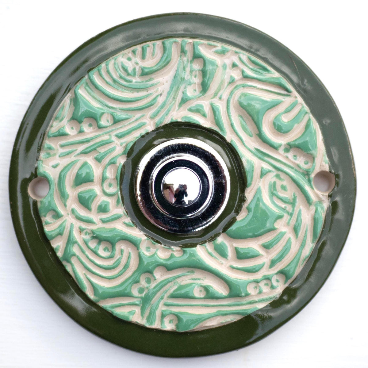 Elegante Keramiktürklingel in Grün mit detailliertem Ornamentdesign und klassischem Druckknopf. Handgefertigt, langlebig und einfach zu montieren.