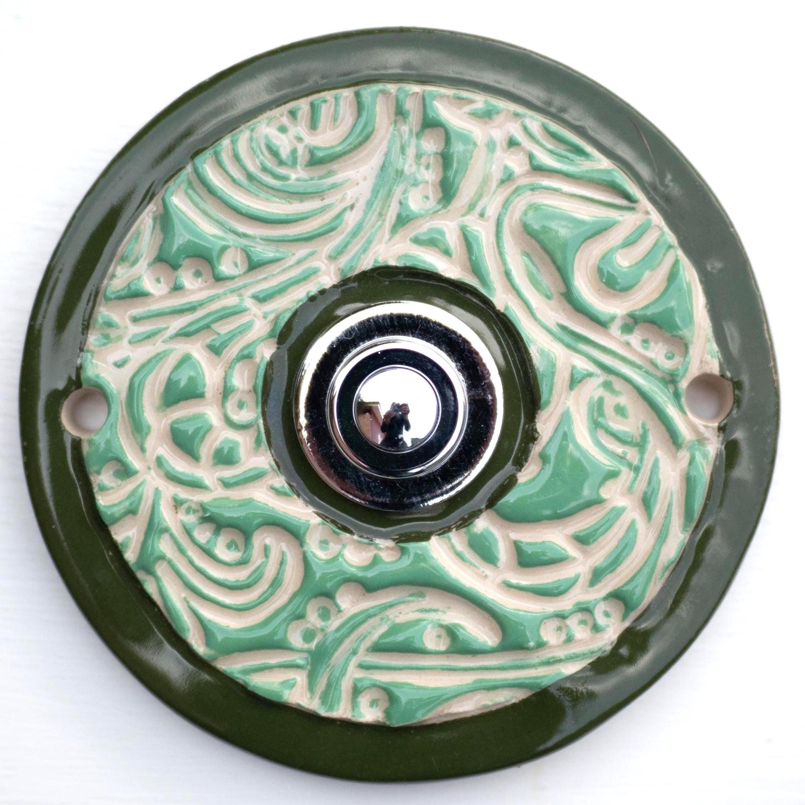 Elegante Keramiktürklingel in Grün mit detailliertem Ornamentdesign und klassischem Druckknopf. Handgefertigt, langlebig und einfach zu montieren.