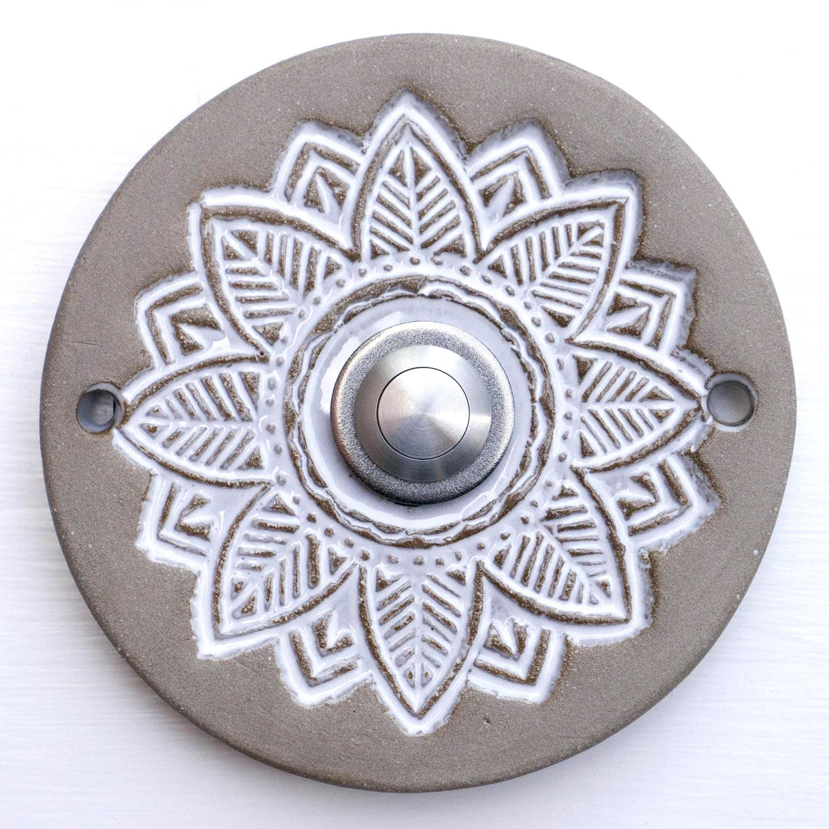 Runde dekorative Klingel mit geprägtem weißem Mandala-Blumenmuster auf grauer Platte und silbernem Druckknopf in der Mitte