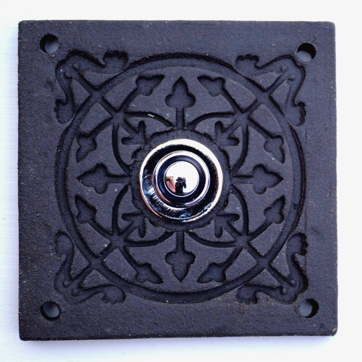 Quadratische Keramikklingel in Rein-Schwarz mit geprägtem Mandala-Muster und silbernem Druckknopf in der Mitte.